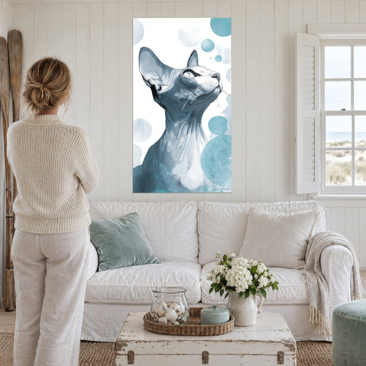 Tableau félin sans poils tête levée, aquarelle bleu ardoise et turquoise, femme de dos au-dessus d'un canapé dans un salon lumineux