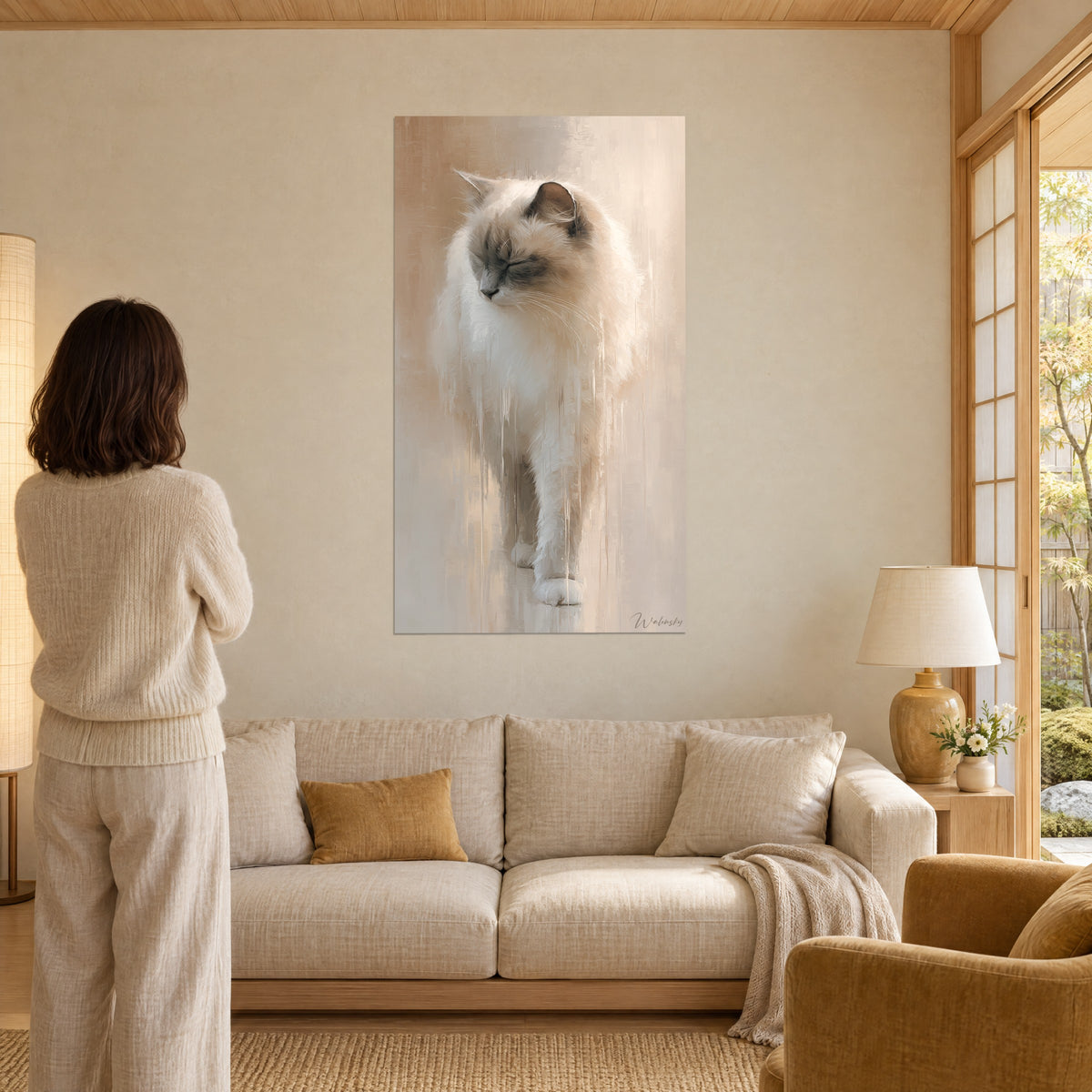 Gemälde Ragdoll-Katze mit geschlossenen Augen, cremefarbenes und taupefarbenes Fell mit Farbläufen, Frau von hinten, über einem Sofa in einem hellen Wohnzimmer