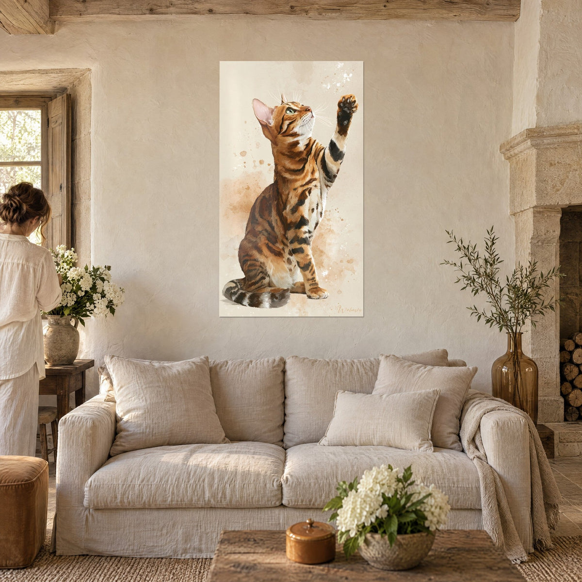 Schilderij zittende Bengalkat, opgeheven poot, oranje vacht met bruine strepen op beige achtergrond, boven een bank in een lichte woonkamer