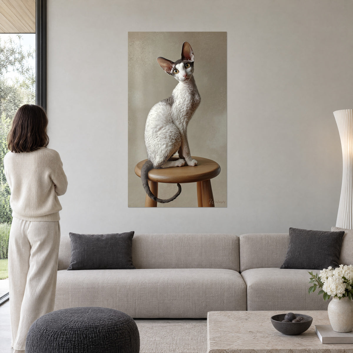 Πίνακας γάτα Cornish Rex με σγουρό λευκό και γκρι τρίχωμα πάνω σε σκαμπό από δρυ, γυναίκα από την πλάτη, πάνω από καναπέ σε φωτεινό σαλόνι