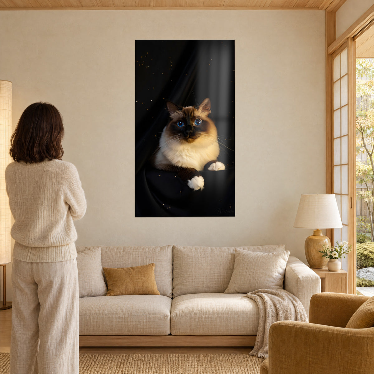 Schilderij heilige Birmaan kat met saffierblauwe ogen, crème en chocoladebruine vacht op een zwarte achtergrond, boven een bank in een lichte woonkamer