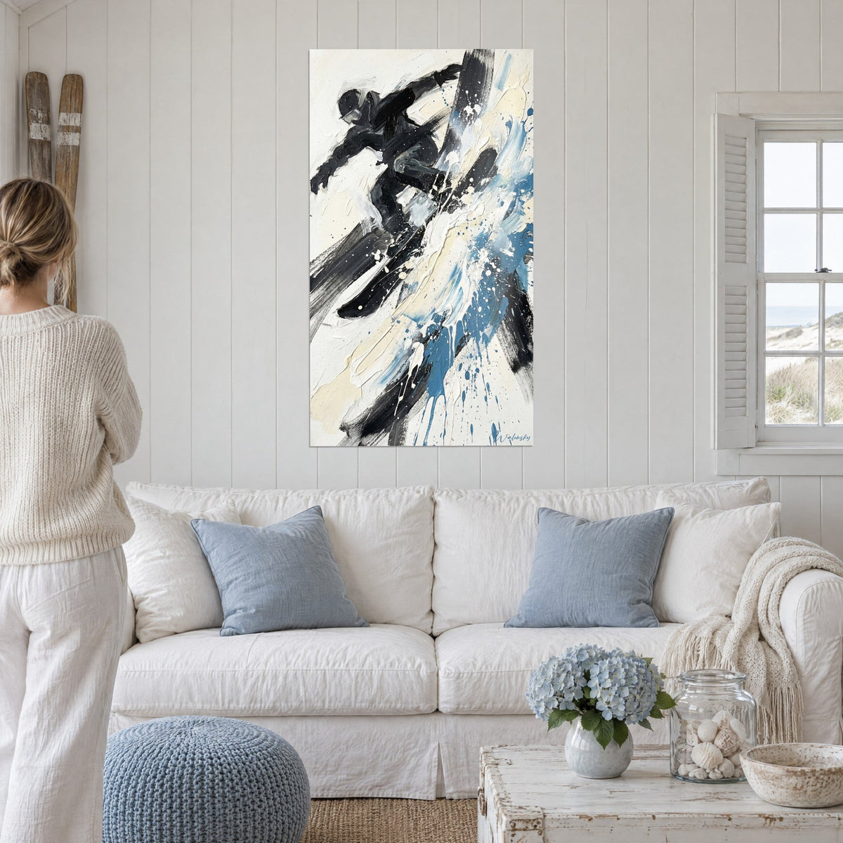 Tableau snowboardeur noir bondissant dans une gerbe de neige bleue et crème, au-dessus d'un canapé dans un salon lumineux