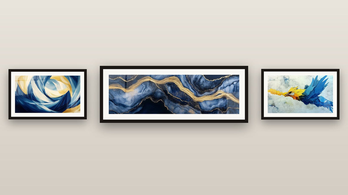 Pared de galería con tres cuadros enmarcados: Mármol Líquido Eternidad Azul, Loro en vuelo y Movimiento Perpetuo