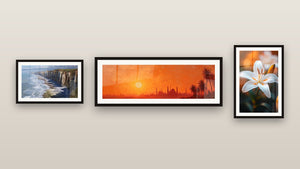 Pared de galería con tres cuadros enmarcados: Acantilados de Étretat, Puesta de sol Estambul y Lirio N°2