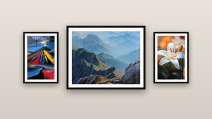 Pared de galería con tres cuadros enmarcados: Volcán estilizado colorido, Paisaje montañoso y Lirio N°2