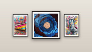Pared de galería con tres cuadros enmarcados: Espiral cósmica azul, Tigre abstracto y Barco colorido