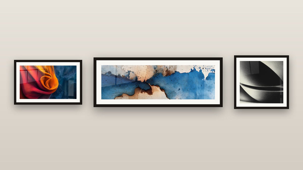 Parete galleria con tre quadri incorniciati: Di tessuto fluido arancione e blu, Astratto blu e beige e Sfera astratta di