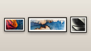 Pared de galería con tres cuadros enmarcados: Tela fluido naranja y azul, Abstracto azul y beige y Esfera abstracta
