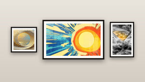 Pared de galería con tres cuadros enmarcados: Ola dorada en espiral, Sol radiante y Vidrio Martini Dorado y Gris entre Humo