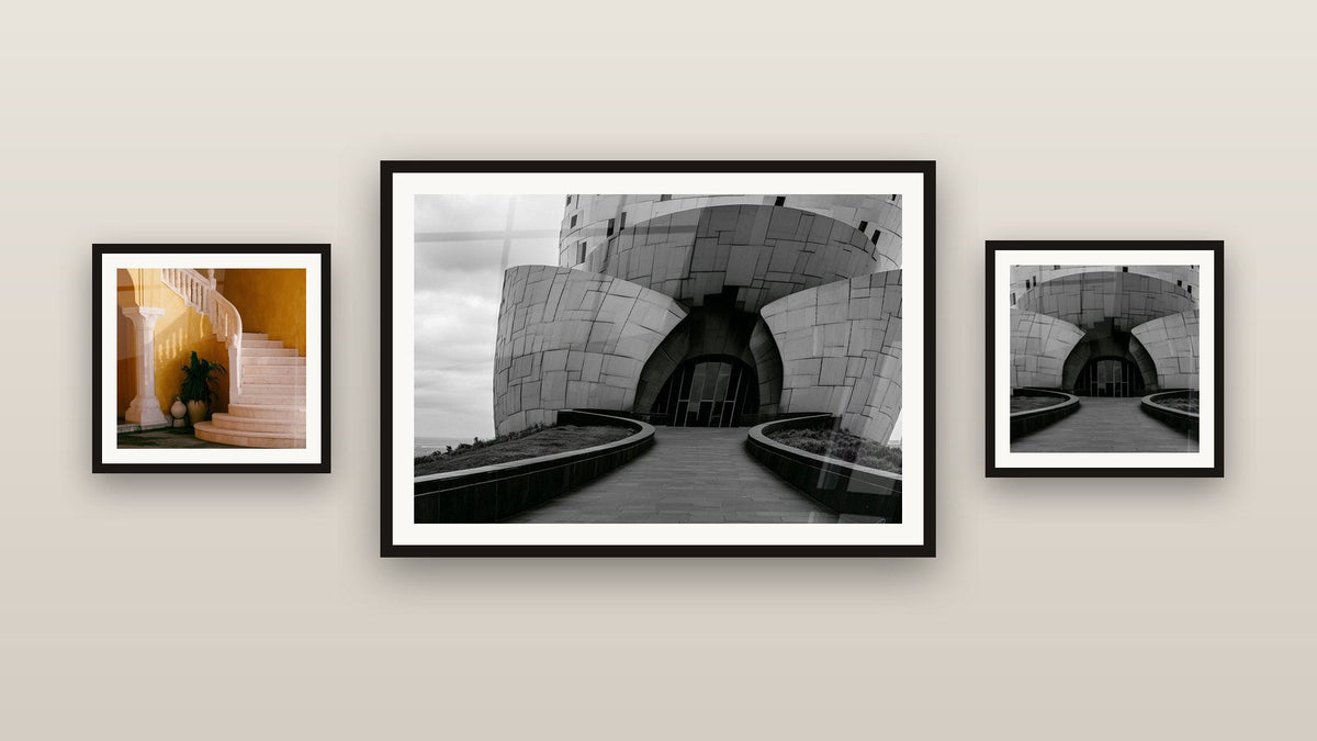 Mur de galerie avec trois tableaux encadrés, dont Escalier courbe ocre et crème mur doré