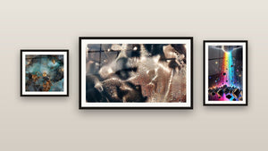 Pared de galería con tres cuadros enmarcados: La Huella de la Eternidad, Cascada de Luz y Galaxia abstracta