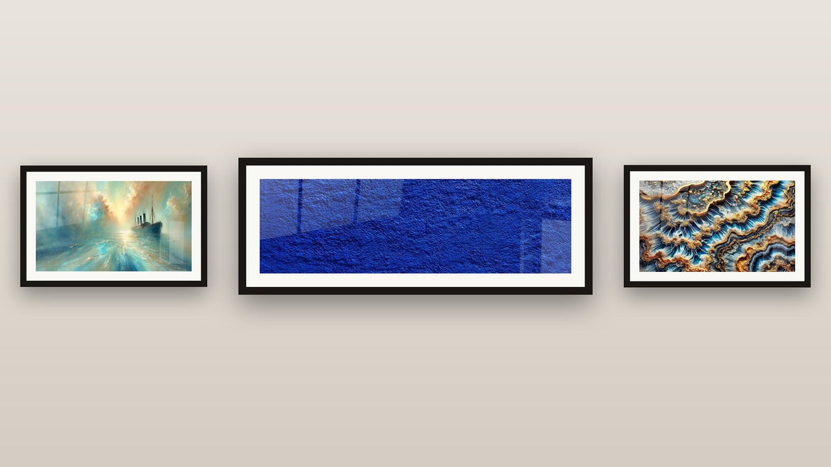 Pared de galería con tres cuadros enmarcados: Textura azul abstracto, En El Corazón de la Brisa y Marea Dorada