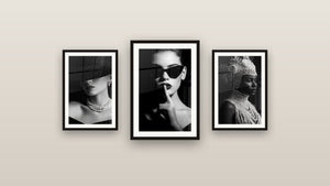 Pared de galería con tres cuadros enmarcados, entre ellos Mujer gafas de sol gesto silencioso