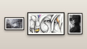 Pared de galería con tres cuadros enmarcados, entre ellos Abstracta caligrafía y Abstracto de rostro femenino