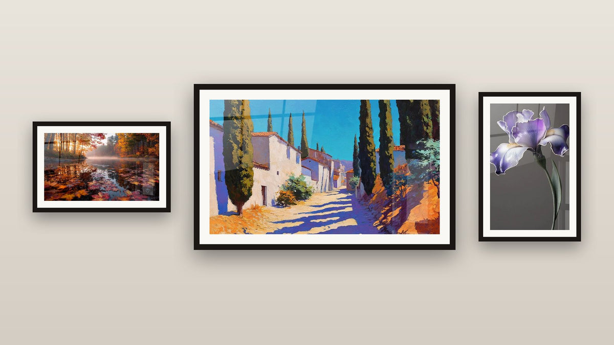 Pared de galería con tres cuadros enmarcados, entre ellos Lago otoñal brumoso y Pueblo mediterráneo con cipreses