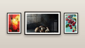 Pared de galería con tres cuadros enmarcados: Champiñones N°1, Cereza N°1 y Vidrio de Cóctel Rojo y Amarillo Soleado