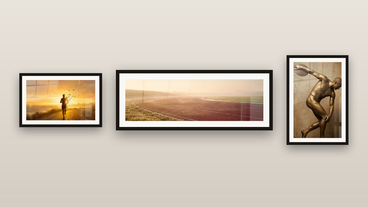 Mur de galerie avec trois tableaux encadrés, dont Piste d'Athlétisme au Coucher de Soleil et Discobolus Bronze