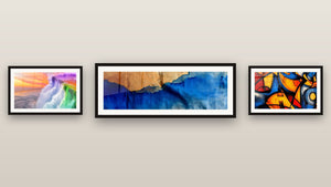 Galerijwand met drie ingelijste schilderijen: Blauwe golven en hout, Regenboogwaterval en Met kleurrijke geometrische vormen