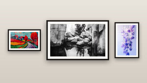Pared de galería con tres cuadros enmarcados, entre ellos Paisaje Rocalloso con Reflejo y Paisaje rural colorido