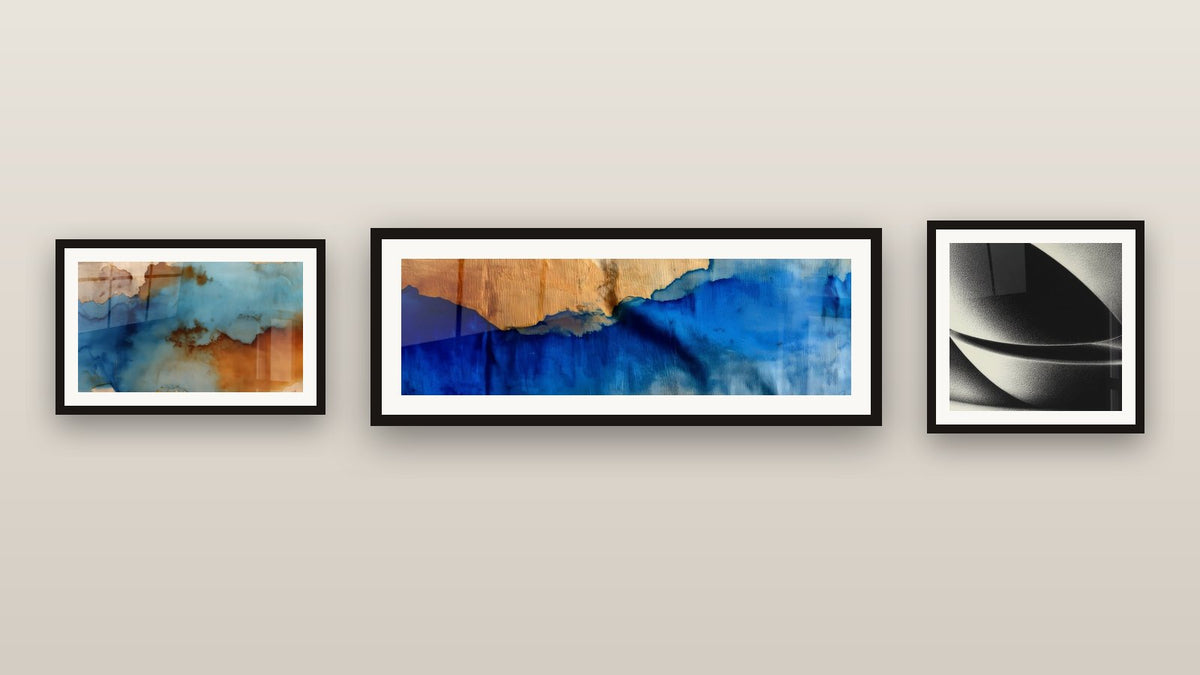 Gallery wall with three framed paintings: Abstract Clouds, Abstract Sphere and Blue Waves and Wood
