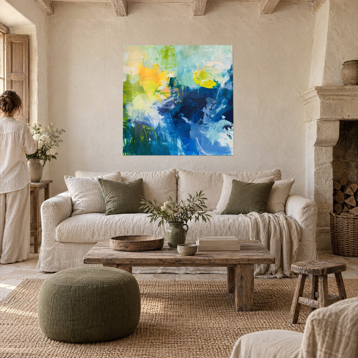 Tableau abstrait aux coups de brosse jaune soleil et bleu marine, personne de dos, au-dessus d'un canapé dans un salon lumineux