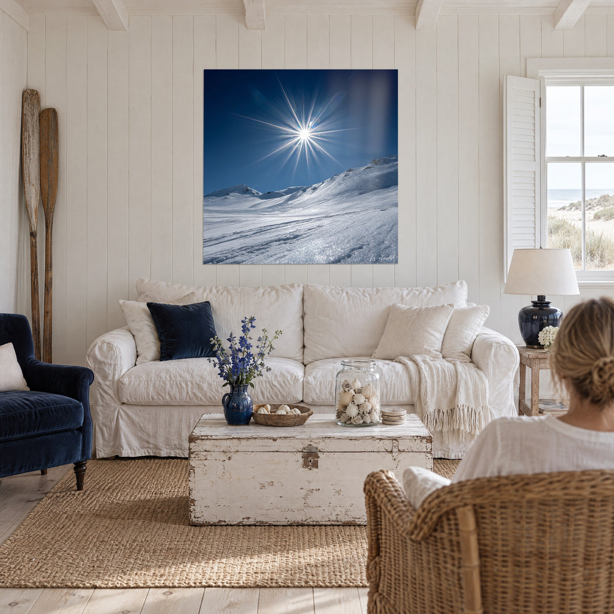 Gemälde Sternensonne mit silbernen Strahlen über makellosem Firn und nachtblauem Himmel, über einem Sofa in einem hellen Wohnzimmer