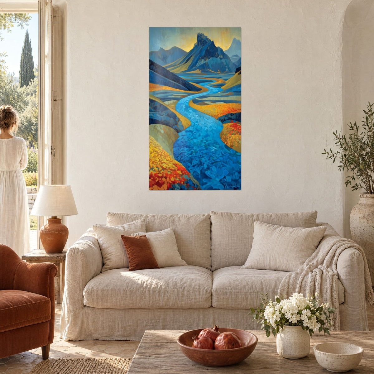 Tableau rivière turquoise serpentant entre prairies orange et rouges, pic bleu au fond, au-dessus d'un canapé dans un salon lumineux