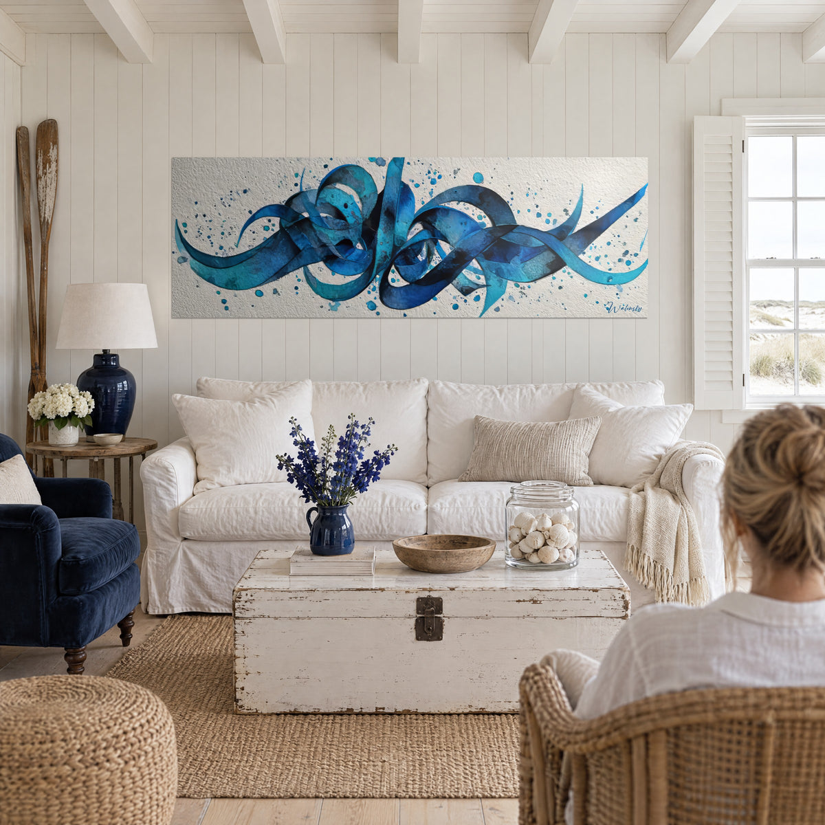 Tableau rubans bleus entrelacés en boucles turquoise et indigo, éclaboussures sur fond crème, au-dessus d'un canapé dans un salon lumineux
