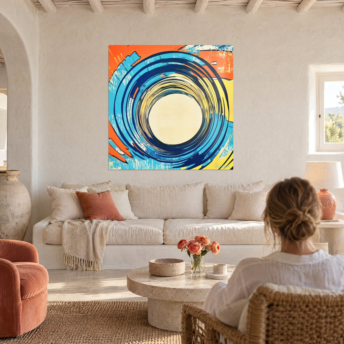 Schilderij met concentrische spiraal in kobaltblauw en fel oranje, crèmekleurig midden, vrouw van achteren, boven een bank in een lichte woonkamer