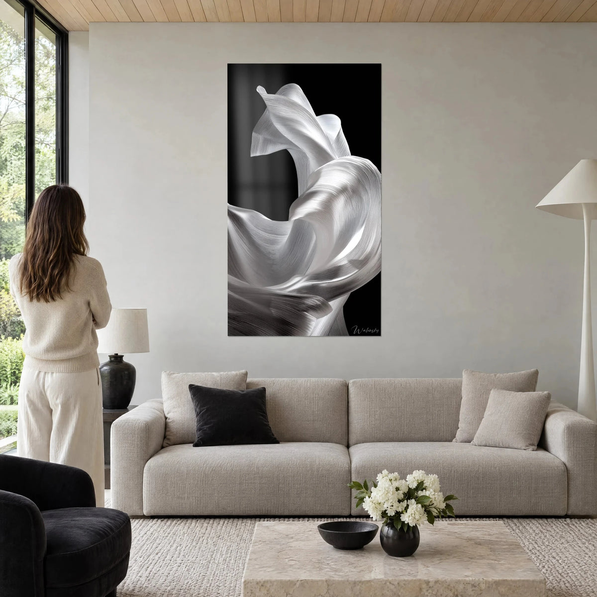 Tableau drapé de soie argentée tourbillonnant sur fond noir, plis blanc nacré, une femme de dos, au-dessus d'un canapé dans un salon lumineux