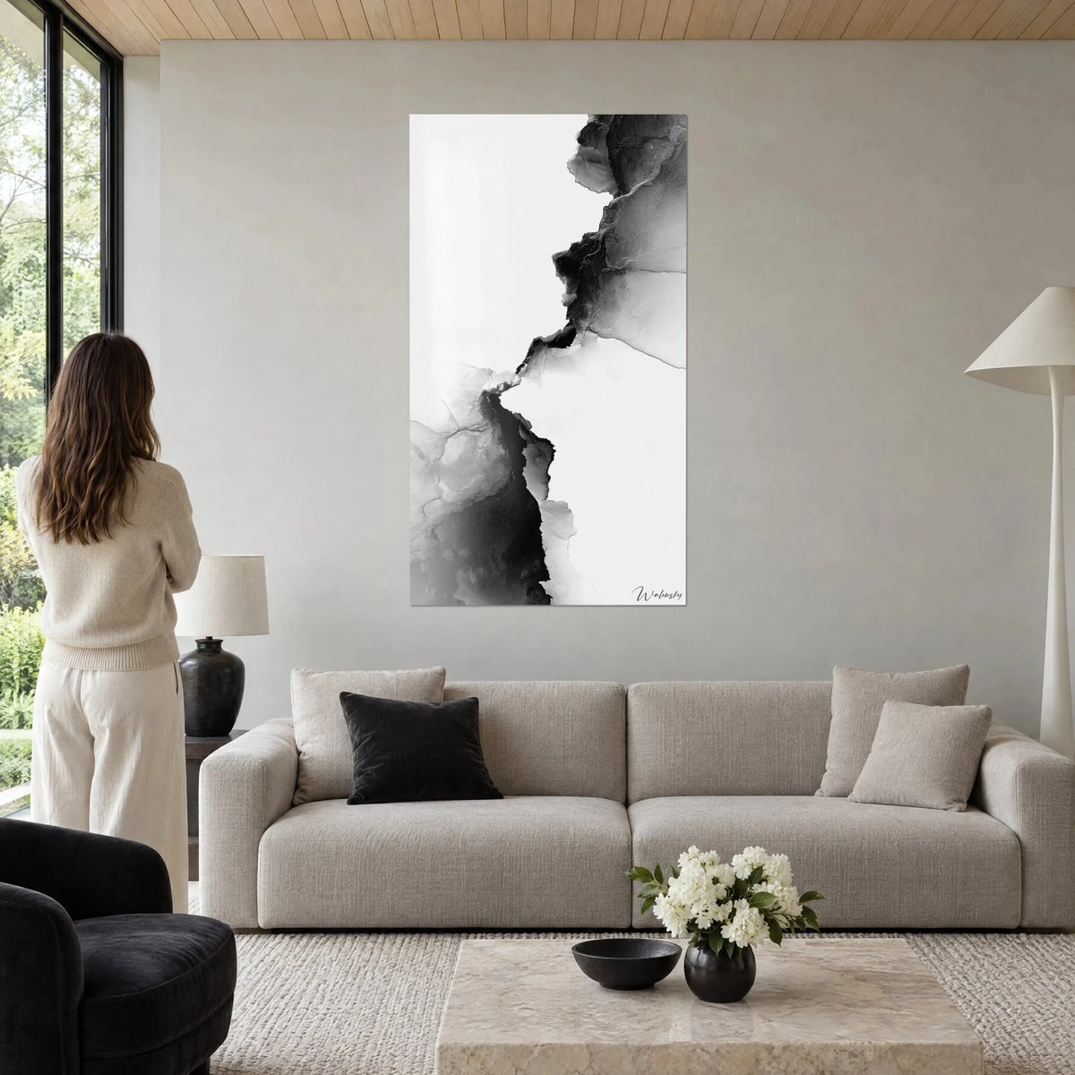 Tableau fissure d'encre noire sur fond blanc, nuances de gris cendré, femme de dos, au-dessus d'un canapé dans un salon lumineux