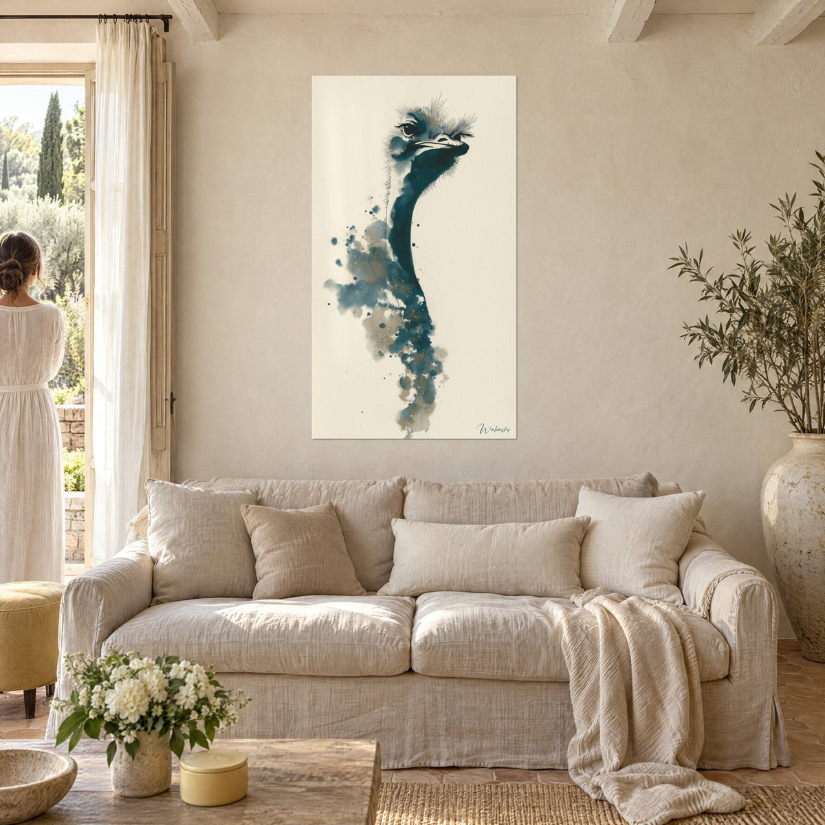 Tableau autruche au long cou bleu pétrole, éclaboussures ocre sur crème, femme de dos, au-dessus d'un canapé dans un salon lumineux