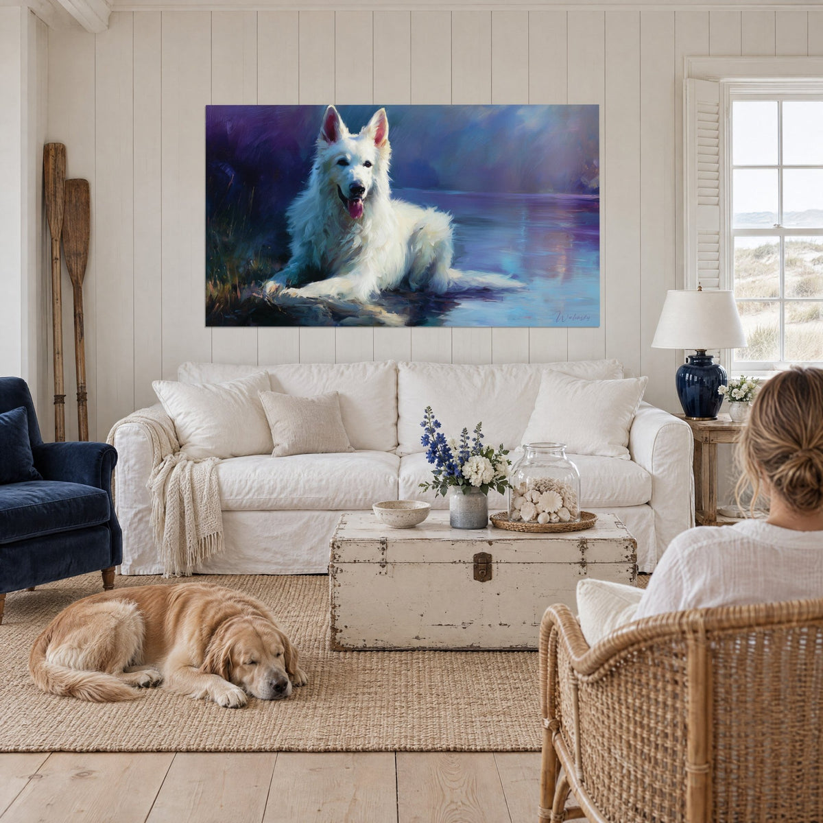 Wall art of a reclining White Swiss Shepherd, ivory coat with violet reflections on the water, above a sofa in a bright living room