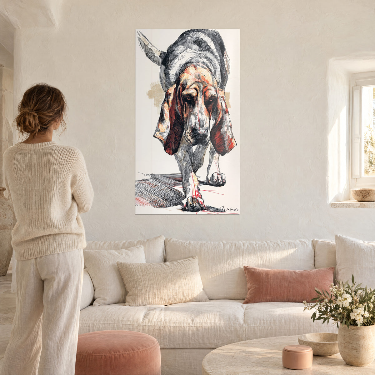 Wall art bloodhound with drooping rust-red ears, black and red line drawing, viewed by a woman, above a sofa in a bright living room