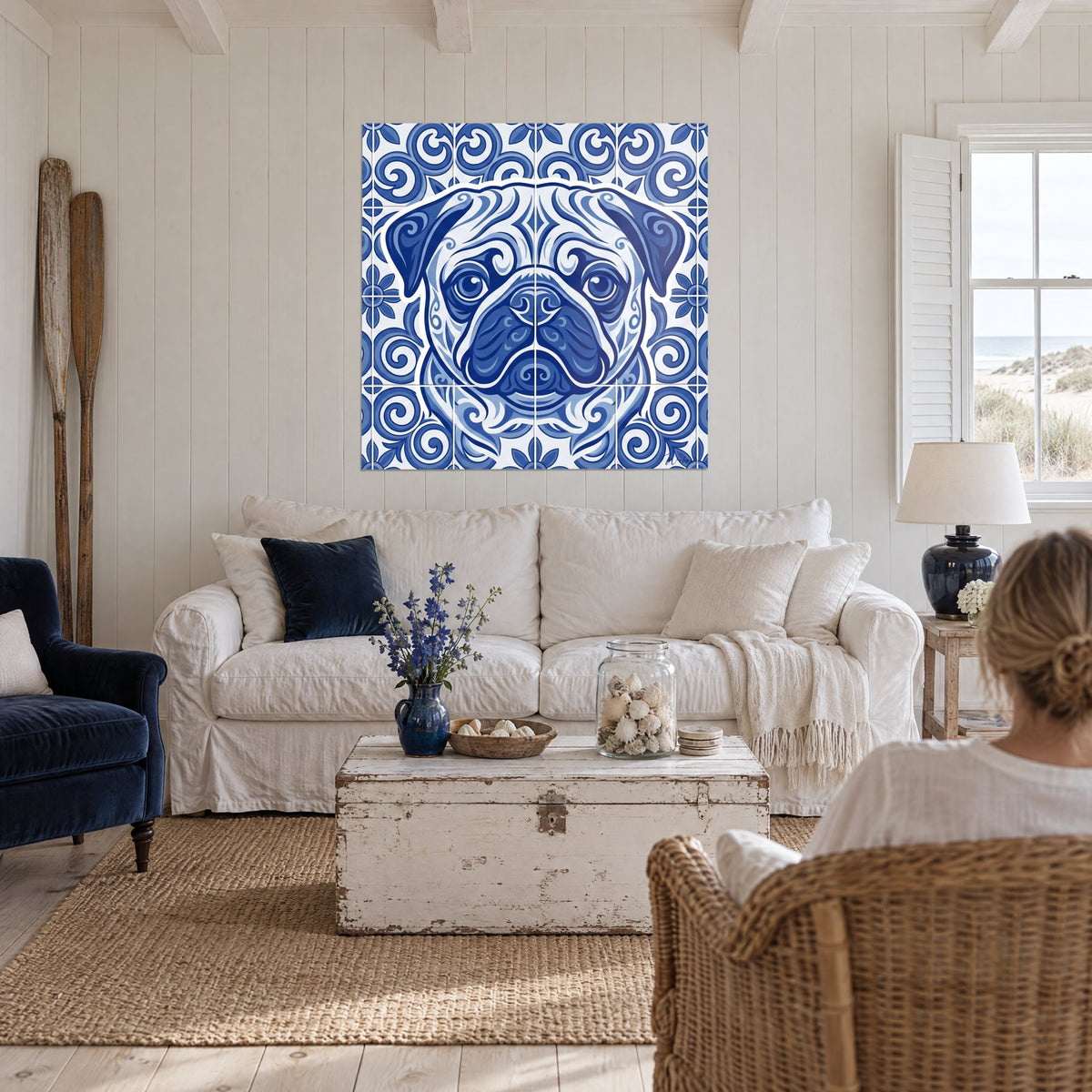 Tableau carlin de face en bleu cobalt sur azulejos blancs, regard rond, deux personnes de dos, au-dessus d'un canapé dans un salon lumineux