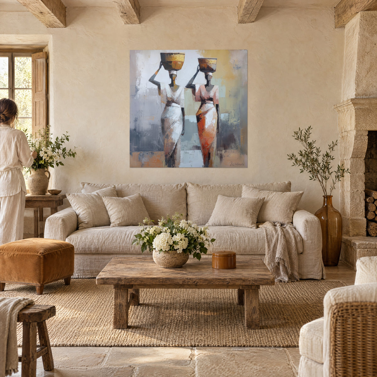 Wall art two water carriers draped in white and coral, golden jars on their heads, above a sofa in a bright living room