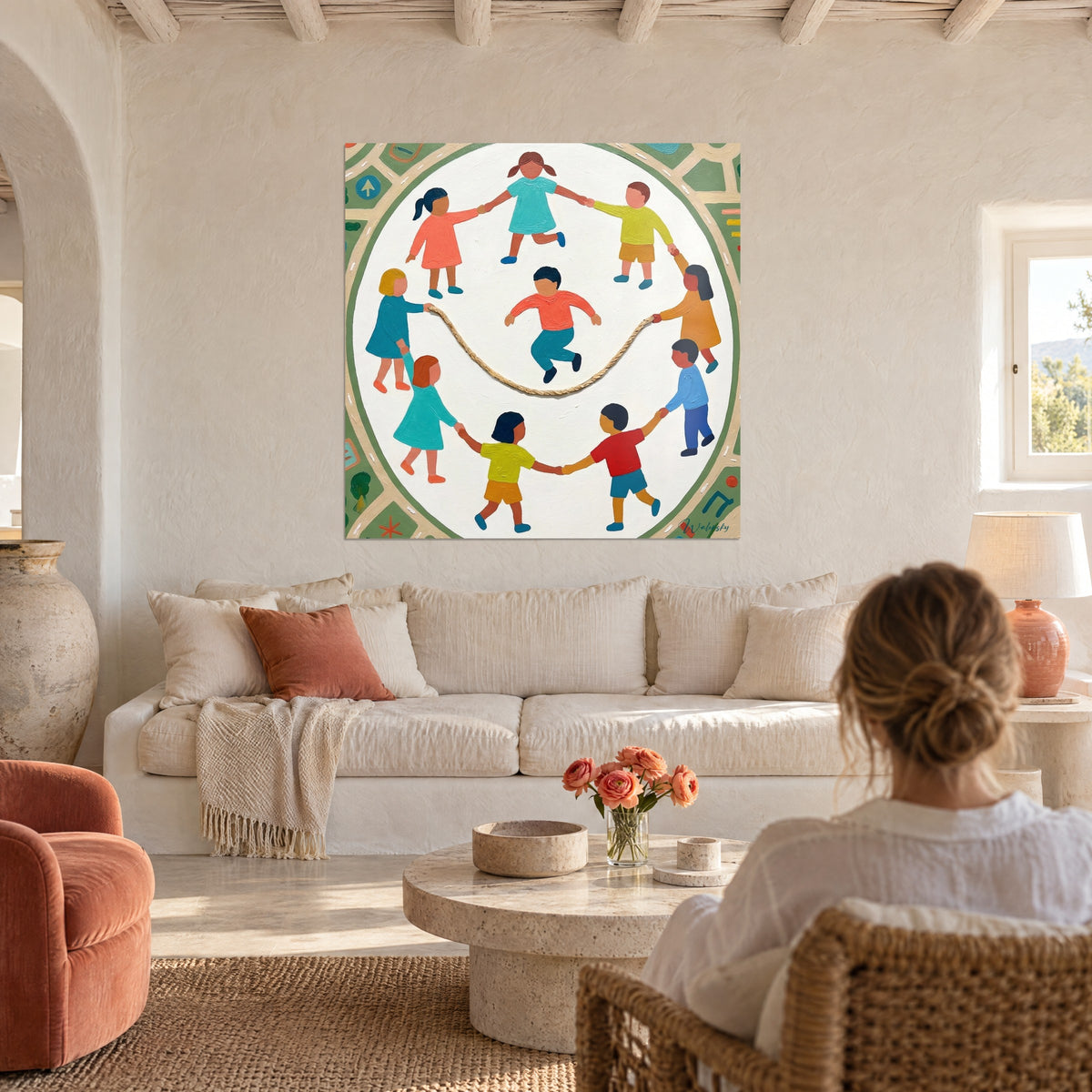 Wall art circle of children holding hands around a beige rope, coral and turquoise clothing, above a sofa in a bright living room