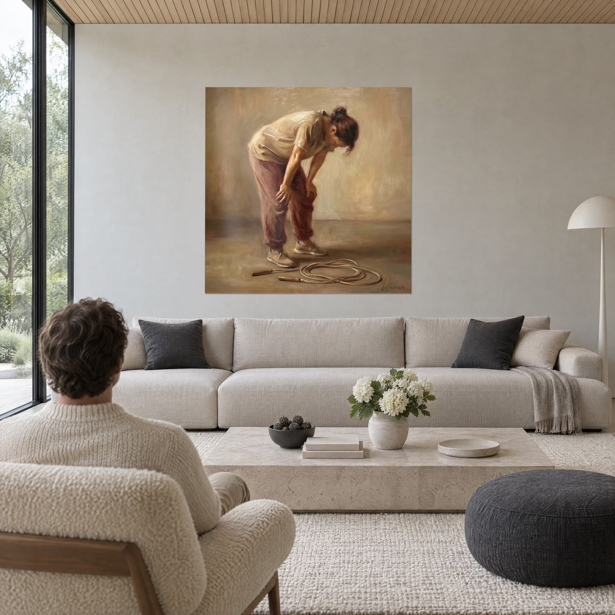 Tableau sportive penchée, mains sur les genoux, pantalon rose poudré et haut crème, corde au sol, au-dessus d'un canapé dans un salon lumineux