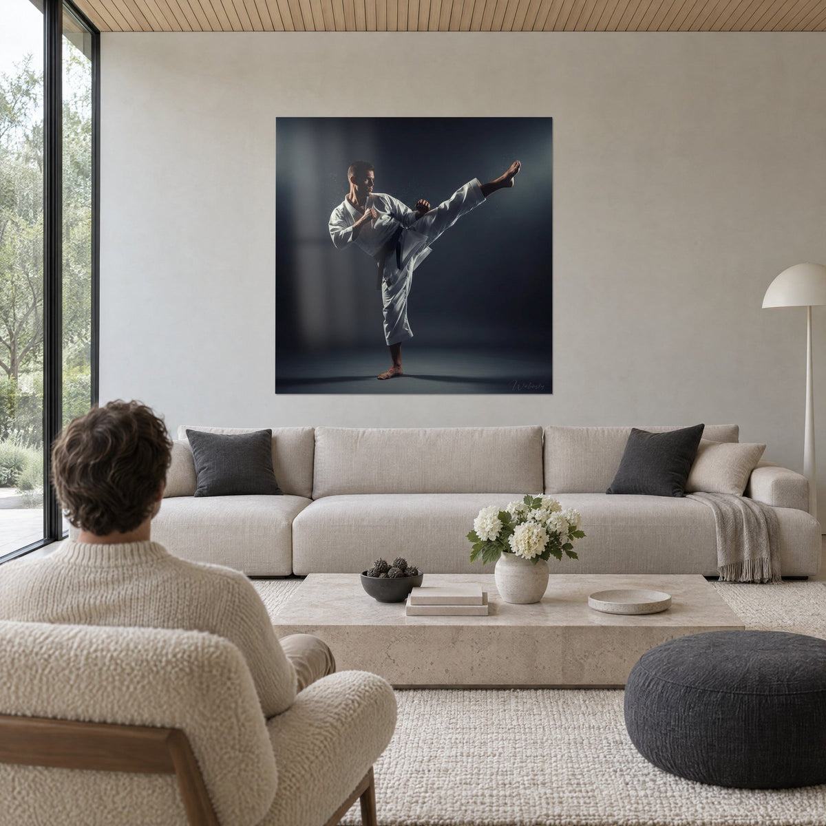Tableau karatéka en kimono blanc, jambe levée en coup de pied haut sur fond gris anthracite, au-dessus d'un canapé dans un salon lumineux