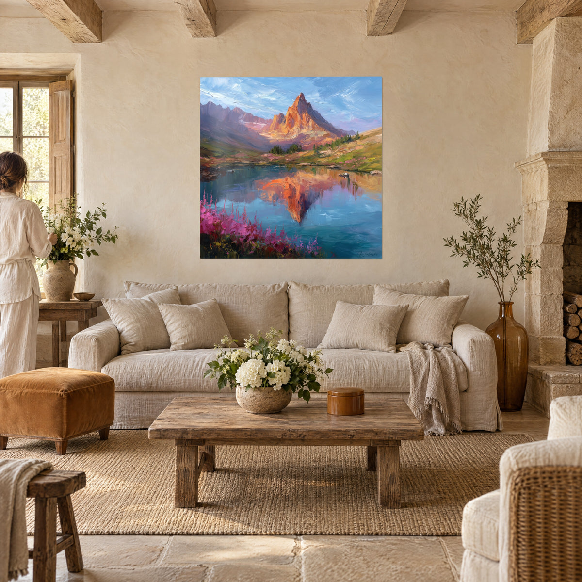 Gemälde eines orangefarbenen Felsgipfels, der sich in einem blauen See spiegelt, rosa Blüten im Vordergrund, über einem Sofa in einem hellen Wohnzimmer