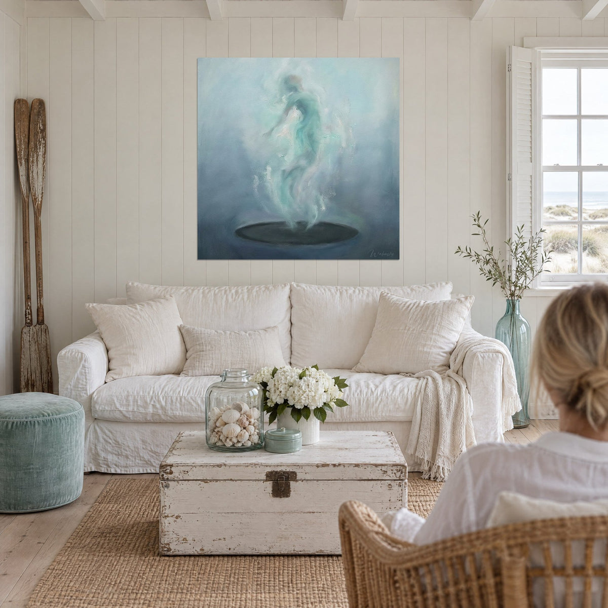 Wall art flowing sea-green silhouette floating, blue-grey mists, dark disc, above a sofa in a bright living room