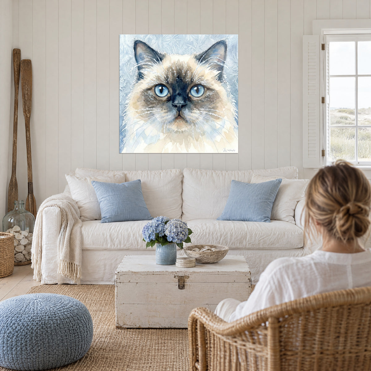 Tableau chat himalayan aux yeux bleus, museau bleu nuit et pelage crème, au-dessus d'un canapé dans un salon lumineux