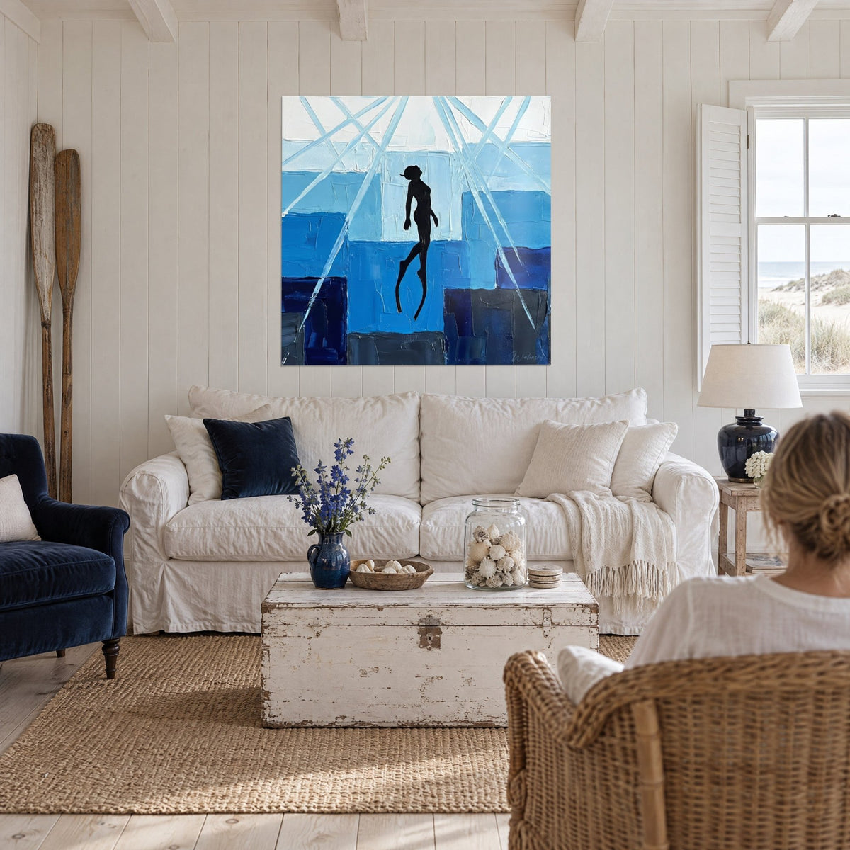 Tableau apnéiste noir tendu vers la surface, bleu turquoise et indigo, rayons blancs en croix, au-dessus d'un canapé dans un salon lumineux