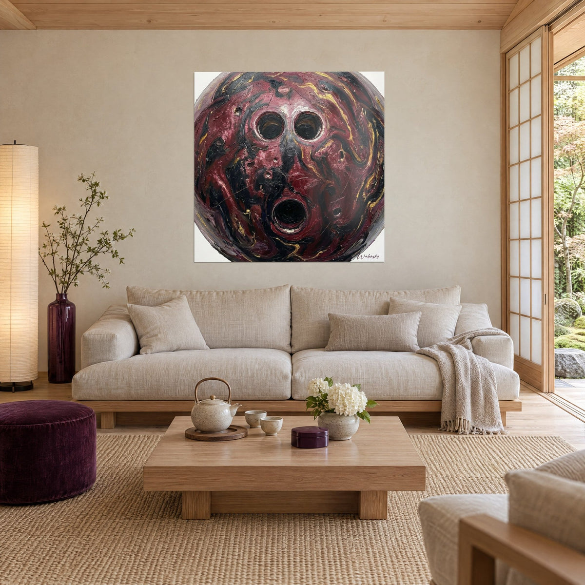 Quadro sfera da bowling bordeaux marmorizzata di nero e oro, tre fori a formare un volto urlante, sopra un divano in un soggiorno luminoso