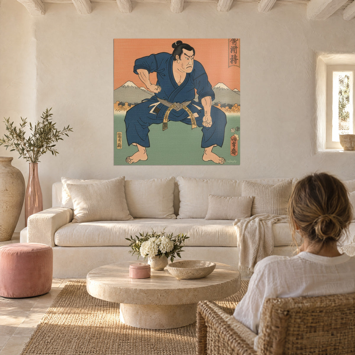 Wall art of a wrestler in an indigo kimono with a golden belt, orange background and snowy mountains, above a sofa in a bright living room