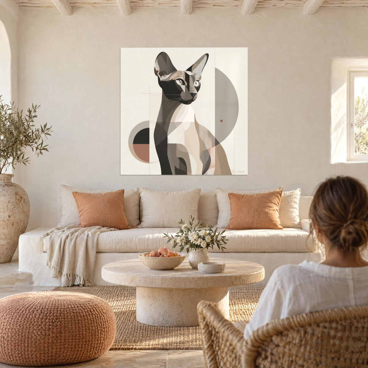 Wall art geometric sphynx cat with upright ears, black and beige, a woman seen from behind, above a sofa in a bright living room
