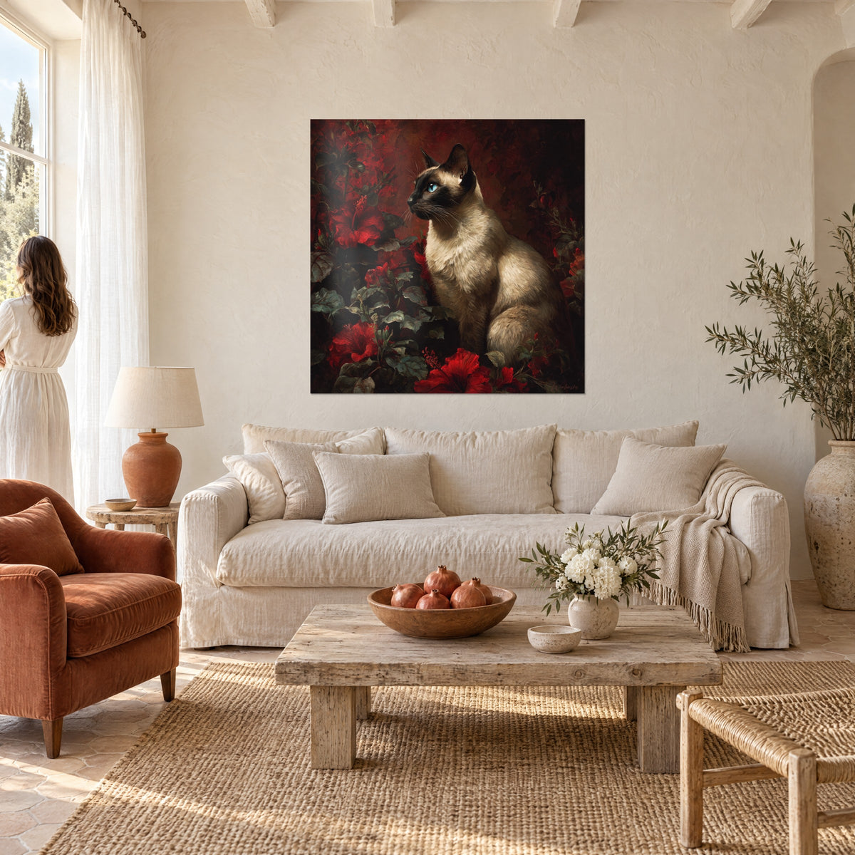 Tableau chat siamois aux yeux bleus assis parmi des hibiscus rouges sur fond bordeaux, au-dessus d'un canapé dans un salon lumineux