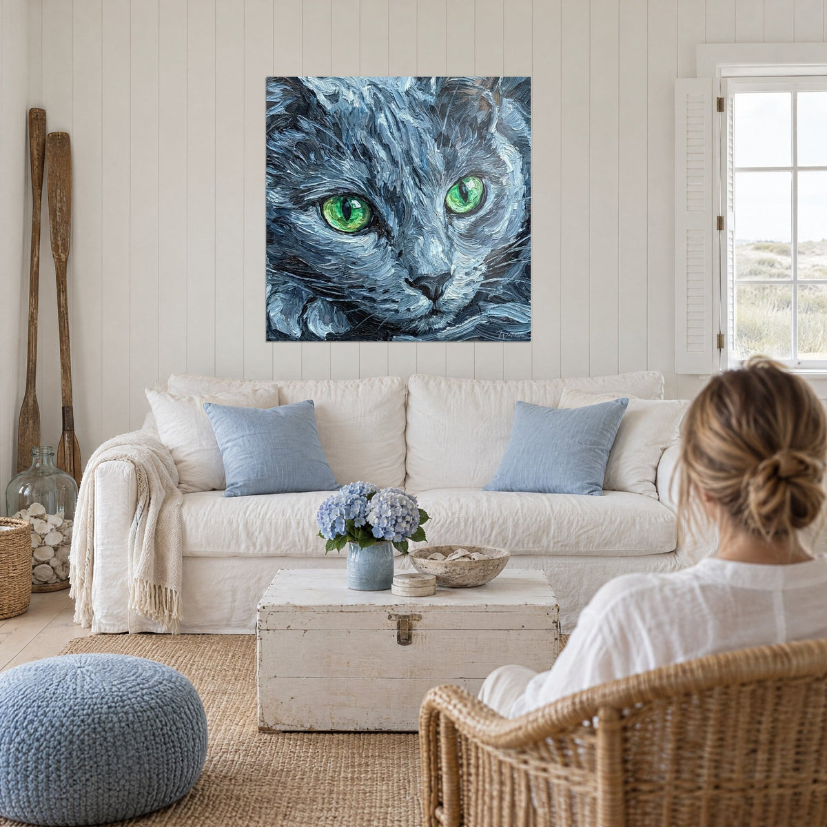 Quadro gatto Russian Blue dal pelo grigio argentato e occhi verde vivo, sopra un divano in un soggiorno luminoso