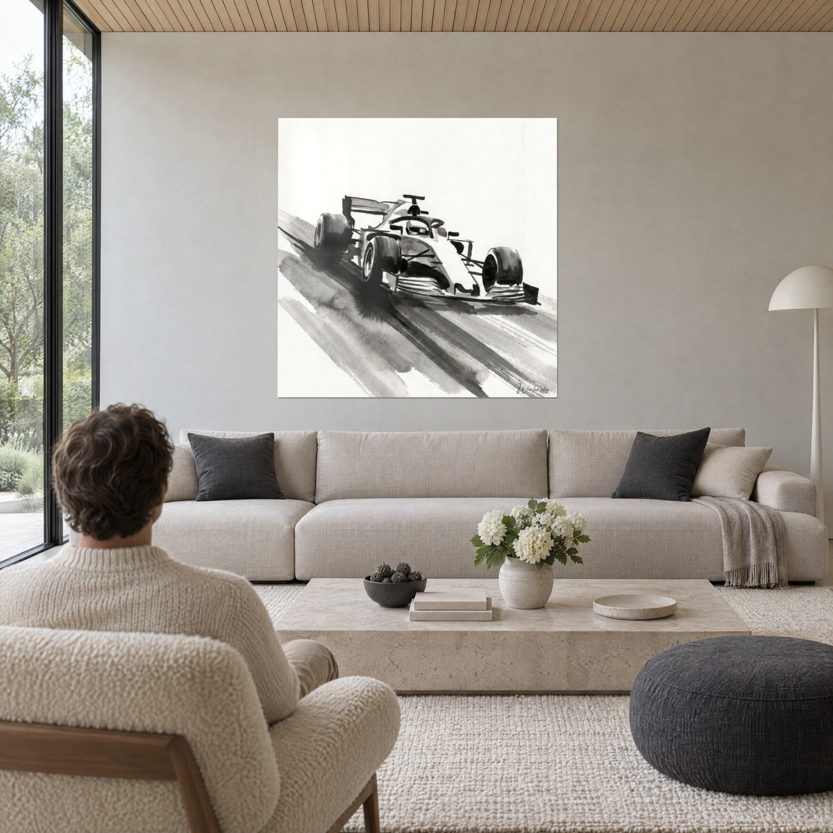 Wall art of a race car taking a corner, black ink and grey wash on ivory background, above a sofa in a bright living room