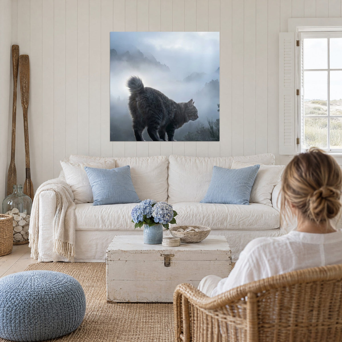 Schilderij bobtail-kat met grijs gestreepte vacht boven een mistig blauw dal, boven een bank in een lichte woonkamer